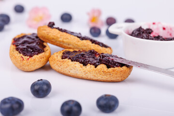Fresh toast with blueberry jam and a jar of sweet jam on a bright white background, in a simple and detailed close-up
