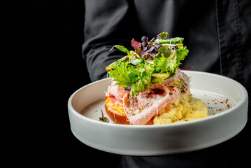 A gourmet dish featuring scrambled eggs and smoked salmon on toast, garnished with fresh herbs, served on a white plate against a dark background. Perfect for breakfast or brunch food photography.