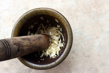 A picture showing a mortar filled with finely pounded garlic, with the pestle still inside.