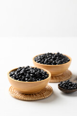 Black bean in wooden bowl with spoon on white background, Food ingredient