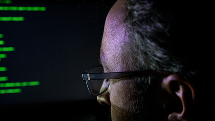 Focused Coder Analyzes Code on Computer Screen in Dark Environment - Cyber security, Cyber Attack, Penetration testing concept.