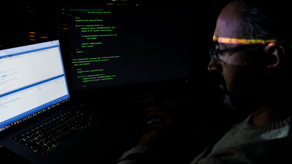Focused Coder Analyzes Code on Computer Screen in Dark Environment - Cyber security, Cyber Attack, Penetration testing concept.