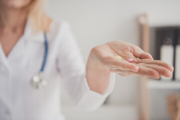 Mature female doctor presenting medication in a clinical setting for patient health and treatment