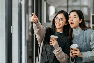 female colleague of half Asian descent holds a cup of coffee and smiles happily.
