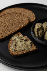 Sliced Rye Bread with Herb Butter on Black Plate