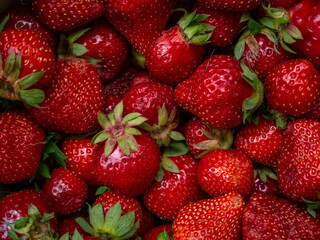 Natural fresh garden red juicy strawberry berries with yellow seeds and green leaves close up top view