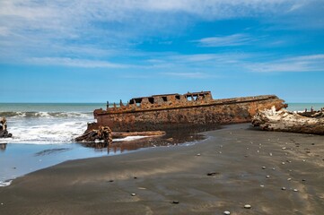 Naklejka premium Rusted shipwreck on a tranquil beach.