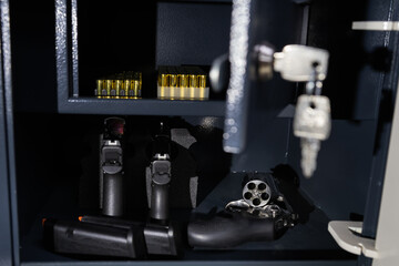 Firearms. Modern pistols, revolver and ammo in a gun safe, close up photo.