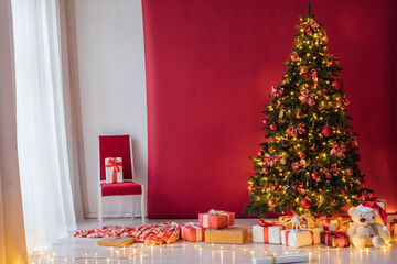 Christmas tree with gifts decorated with toys in the interior of a red and white room