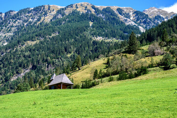 Obraz premium Wooden Chapel on Alpine Meadow