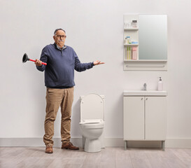 Confused mature man holding a toilet plunger