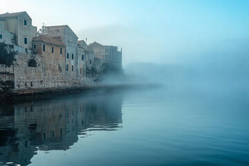 Misty morning view of ancient buildings along the water