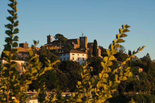 Vista di Montecatini Alto durante una serena giornata soleggiata cielo azzurro e sereno senza nuvole bianche sull'orizzonte durante un tramonto incorniciato tra due alberi.