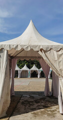 White event tents arranged outdoors on a sunny day with a bright blue sky.