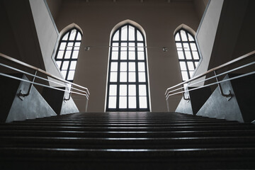 Majestic Staircase Leading to a Backlit Arched Gothic Window: A Perspective from Bottom to Top