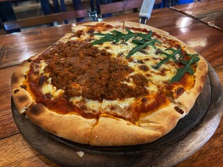 Delicious Italian-style pizza served on a wooden plate in a warm and homely atmosphere.