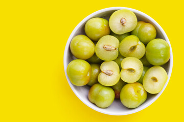 Fresh green plum fruit on yellow background.