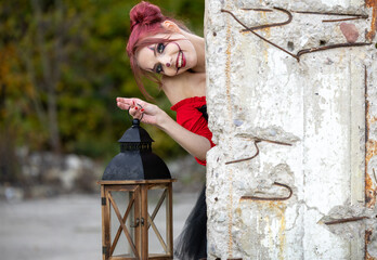 Young Beautiful Woman in Halloween Spirit: Peeking from Behind the Corner with a Lantern in the Forest