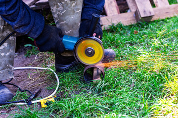 A worker cuts a metal part using an angle grinder.