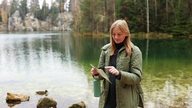 high quality video woman pointing in map near mountain lake and rock formation. duck swimming on mountain lake 