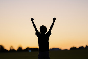 Fototapeta premium Silhouetted against a vibrant sunset, a young boy stands triumphantly with his arms lifted high, embodying pure joy and freedom in an expansive field. Generative AI
