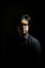 Fototapeta premium low key portrait of young Asian man in serious profile on black background