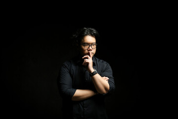 Low key portrait of a man. Asian man in black shirt over black background