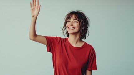 A woman wearing a bright red shirt is waving one of her hands, likely to get attention or express excitement