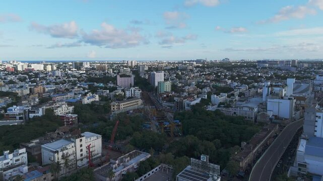 A breathtaking aerial video captures Chennai city bathed in the golden hues of sunset. From a bird's-eye view, the city's sprawling urban landscape unfolds, with its intricate network of roads