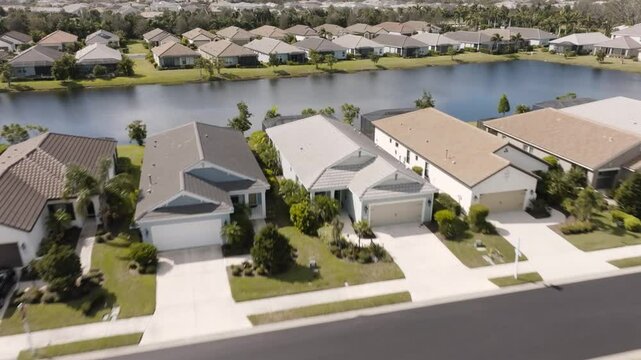 drone shot of a suburban community in Florida on a sunny day with most houses in the neighborhood looking alike. Drone flying over homes and lake