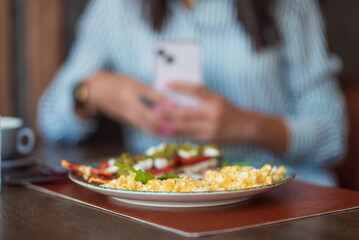 Woman taking a picture of scrambled eggs with smartphone in a restaurant