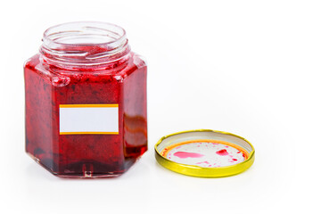 An open hexagonal glass jar of homemade red currant berry or cranberry jam with a gold lid beside...