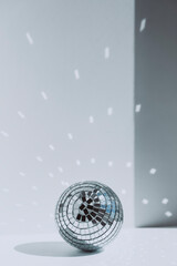 Shiny disco ball in front of wall at home in sunny day, copy space.