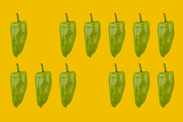 Fresh green chili peppers on yellow background