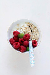 Bowl of oatmeal with yogurt and fresh raspberries