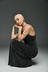 A bald young woman radiates confidence in a stylish outfit, highlighting her beauty.
