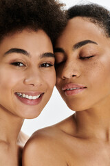 Two women share a moment of joy and closeness, showcasing natural beauty and warmth.