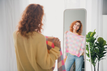 Fototapeta premium Photo of shiny cute girl dressed yellow jumper trying on new sweater indoors house apartment room