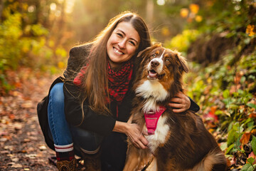 Loving young woman with her shepherd Australian on fall season