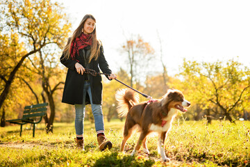 Loving young woman with her shepherd Australian on fall season
