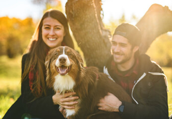 Loving young couple together outdoors with shepherd Australian dog on fall season