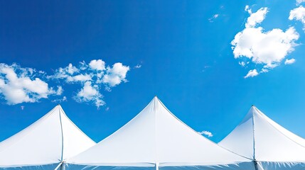 Low angle view of sections of a pristine white tent contrasting with a bright blue sky, ideal for capturing the essence of outdoor events with ample copy space.