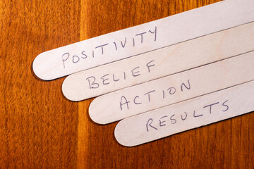 Positive living concept - Positivity, Belief, Action, Results handwritten on wooden popsicle sticks...