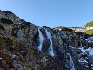 The Wielka Siklawa waterfall in the Valley of Five Ponds, Tatra Mountains, Zakopane, Poland, cascades dramatically over rocky cliffs, creating a mesmerizing scene in this alpine landscape.