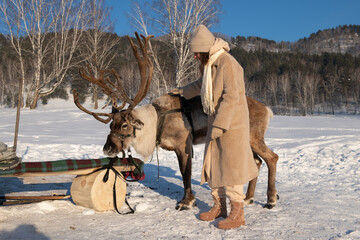Naklejka premium Young woman with deer with beautiful horns in winter landscape