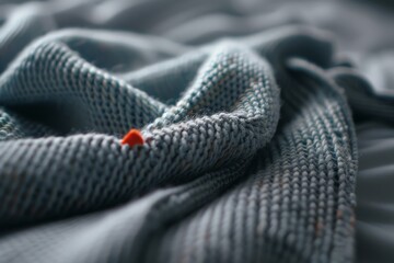 Fototapeta premium A soft, knitted blanket with a single red strand stands out, showcasing intricate texture and the warmth of handmade comfort.