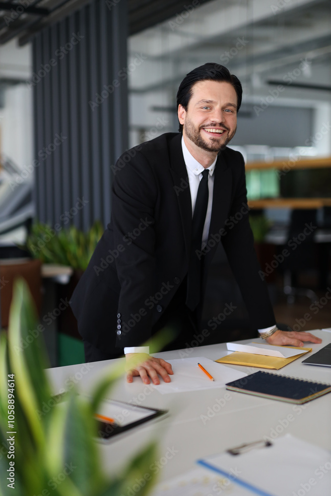 Aufkleber a man in a suit is smiling and standing in front of a desk with papers and a laptop. concept of prof