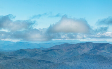 Fototapeta premium The Appalachian mountains are bathed in a soft blue light layered in shades of blue, aqua, and pale green while an aqua blue sky with large, soft clouds drifts above them. Horizontal.