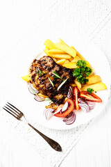 Grilled Steak with french fries and fresh tomatoes. White wooden background.