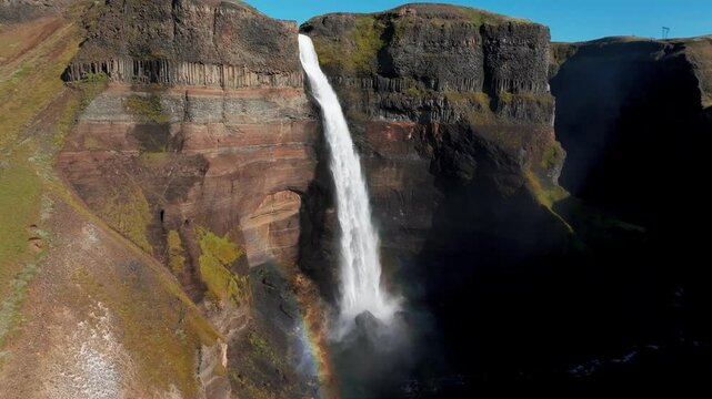 Majestic Haifoss Waterfall With Rainbow On Rugged Cliff In South Iceland. orbiting drone shot